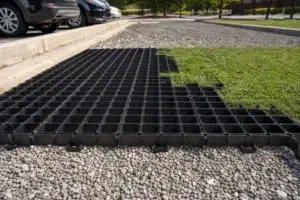Illustrative open-cell HDPE grass paver placed over a prepared gravel base near a parking area