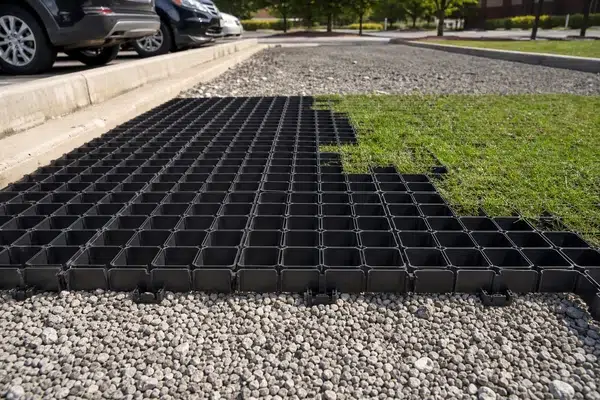 Illustrative open-cell HDPE grass paver placed over a prepared gravel base near a parking area